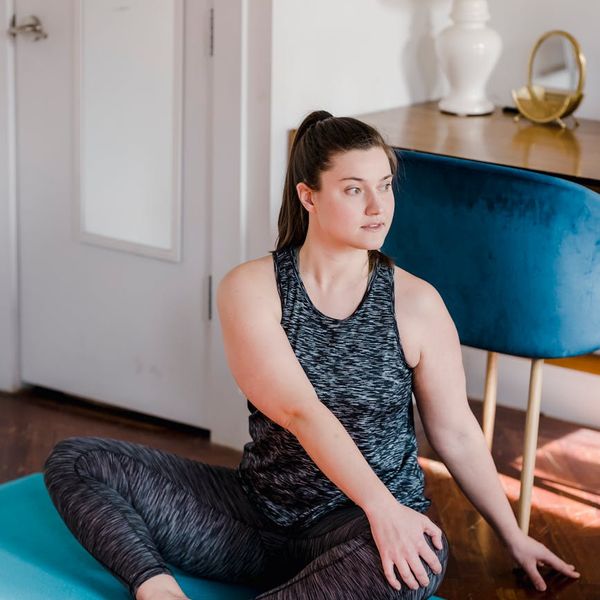Person stretching on a yoga mat in a well-lit, calm environment, focusing on well-being.